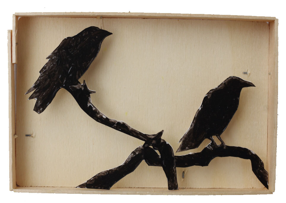 Zwei Raben sitzen auf Ästen, ausgeschnitten aus Polystyrol und mit Abstand in eine Holzschachtel geklebt