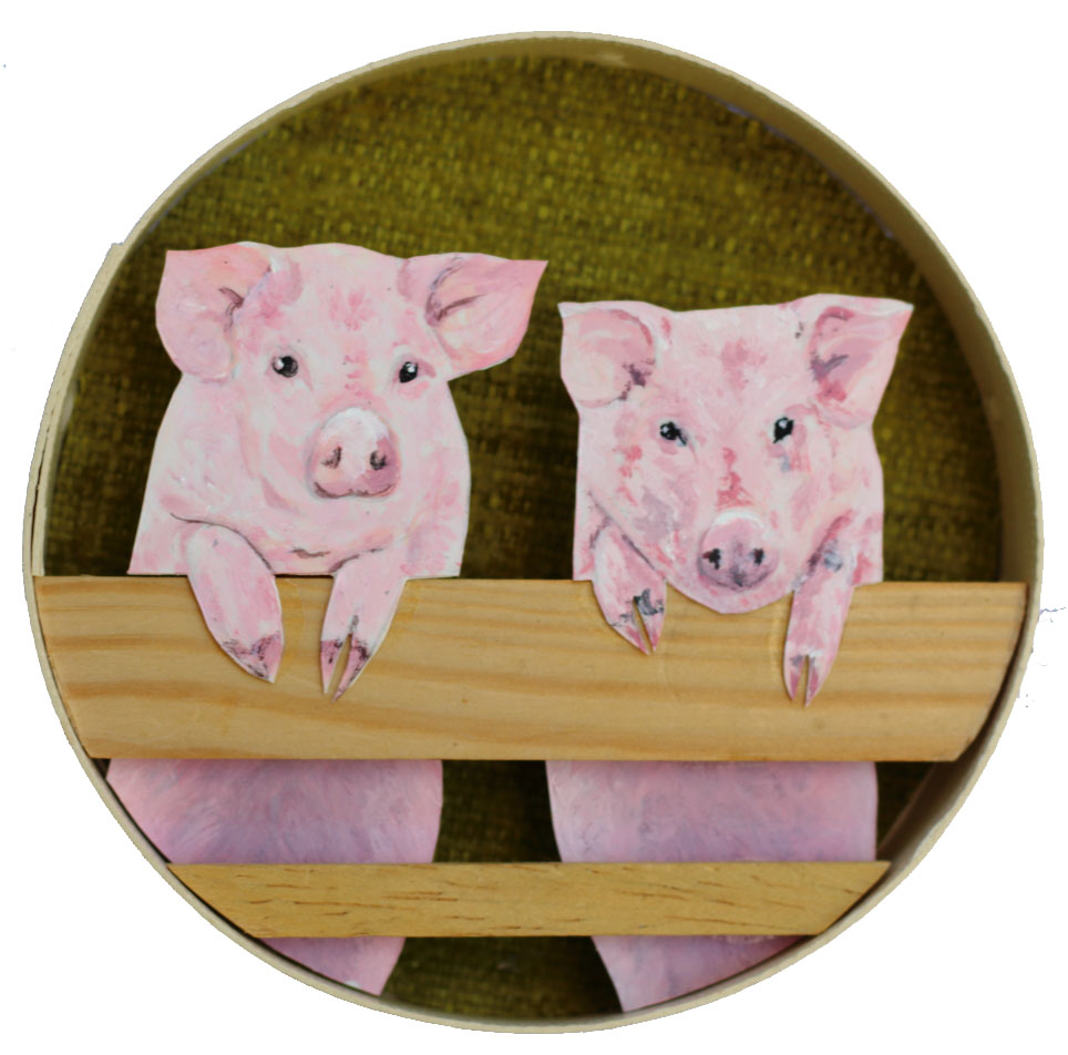 Zwei Schweine ausgeschnitten aus Polystyrol lehnen über Holzstäbchen als Zaun in einer runden Sperrholzschachtel